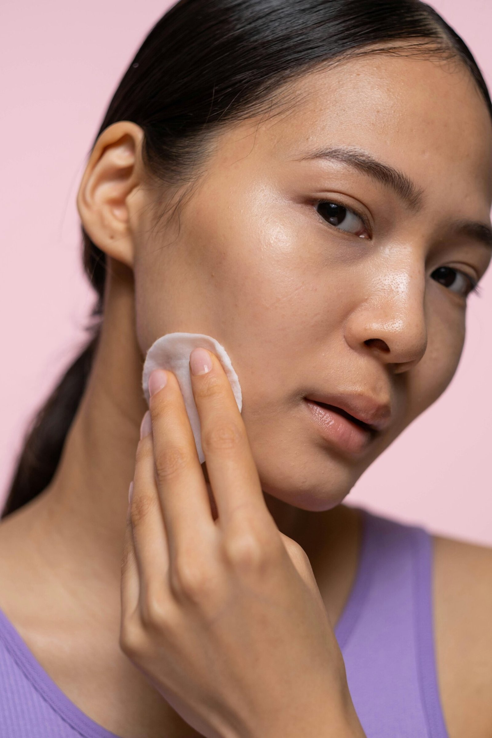 Close-up of a young woman applying skincare for healthy and glowing skin.